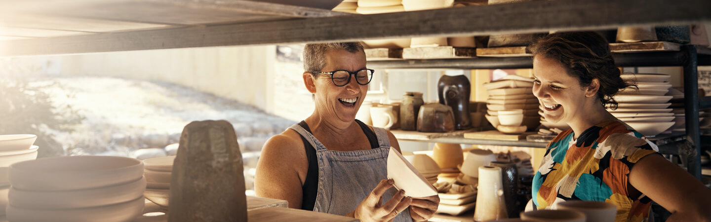 Two women laughing at a pottery shop