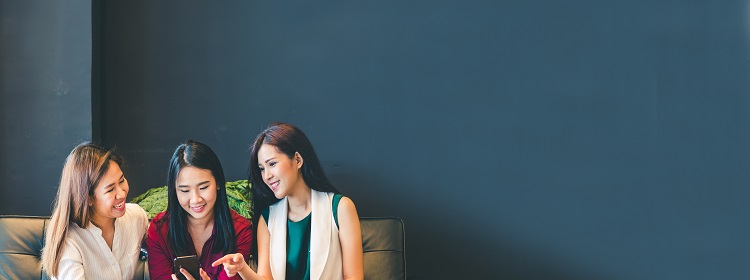 Three young professional women talking on a couch