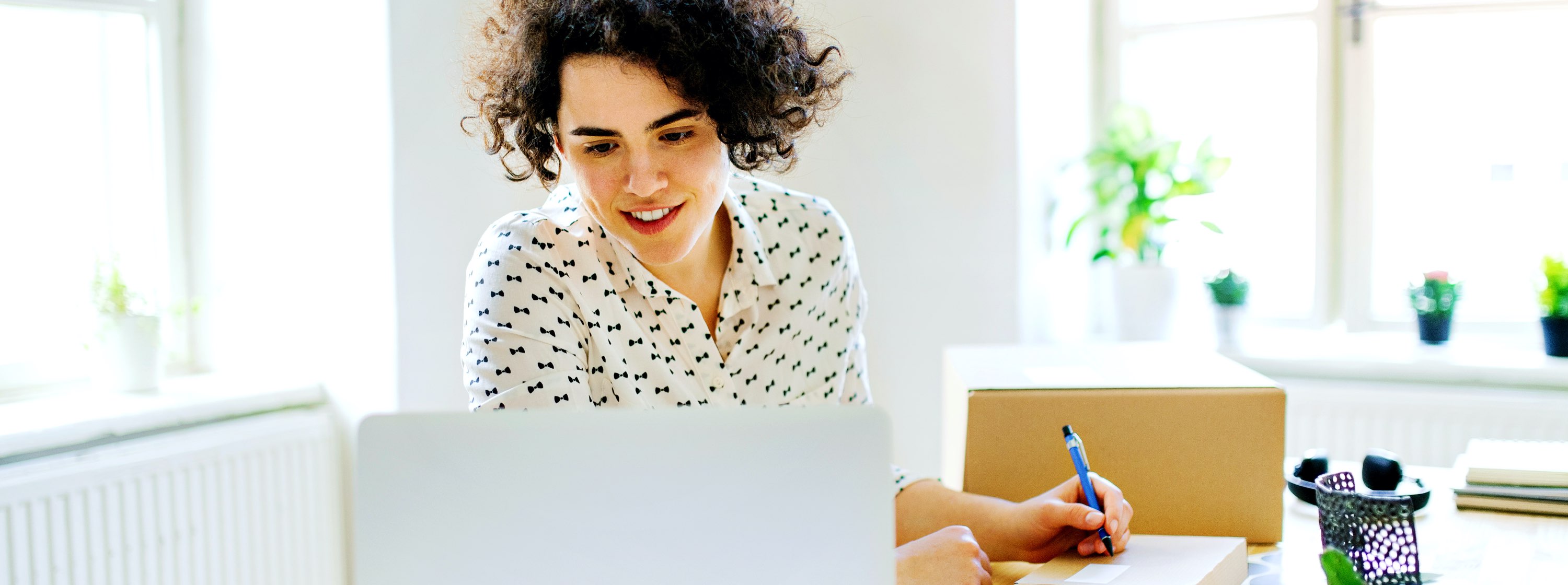 Women working on an office computer taking notes