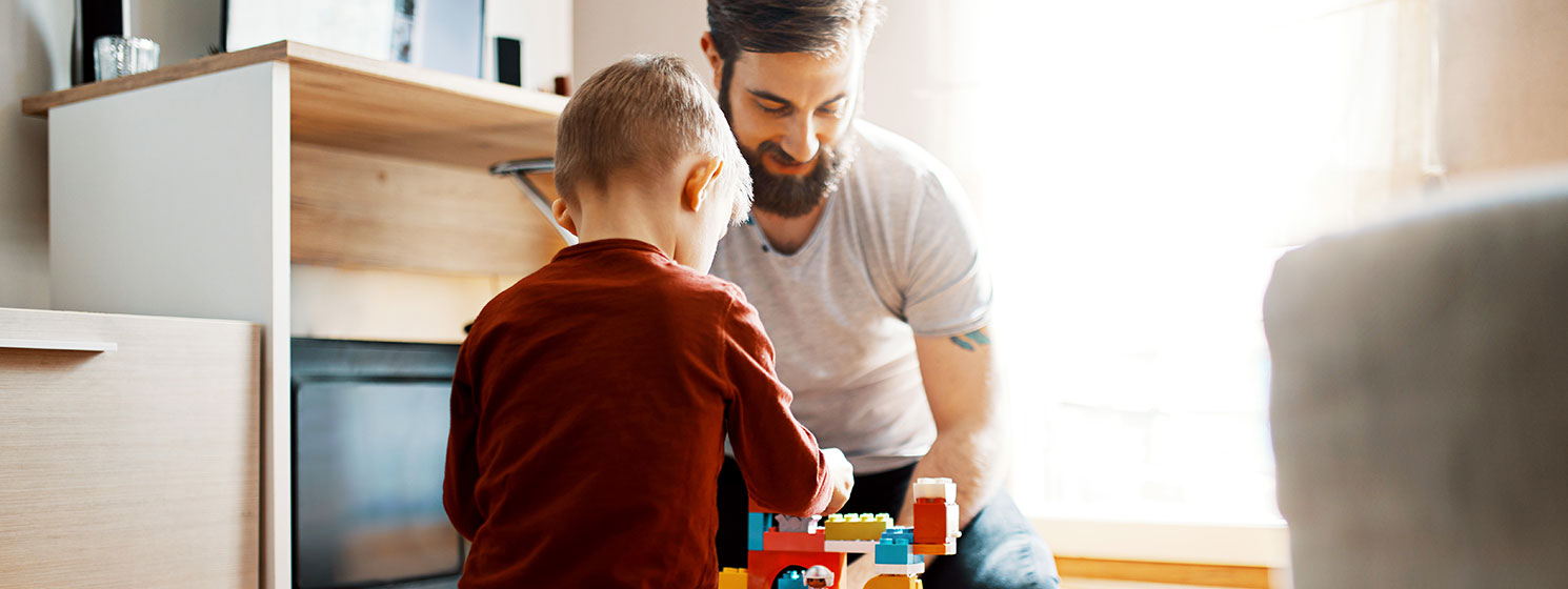 Father and young son, at home playing Lego.