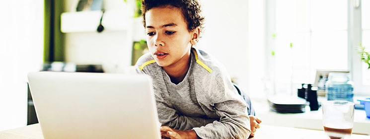 young boy looking at a laptop in a kitchen