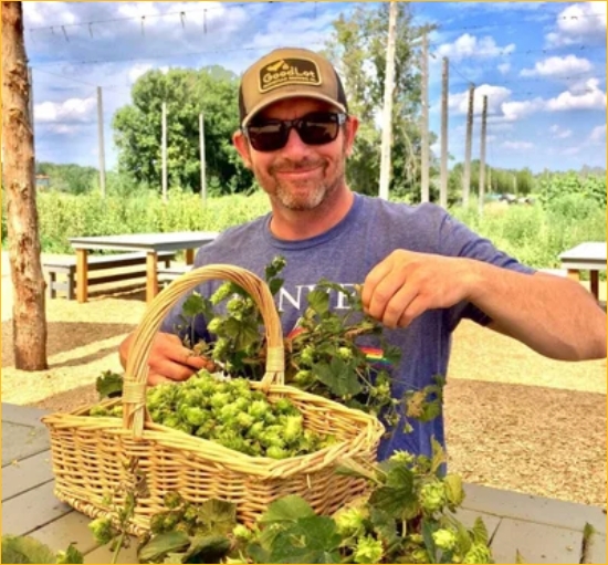 Phil Winters, one of the owners of Goodlot Farm and Farmstead Brewing, smiling and wearing a Goodlot hat and sunglasses. 