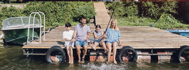 family sitting on a dock at their cottage