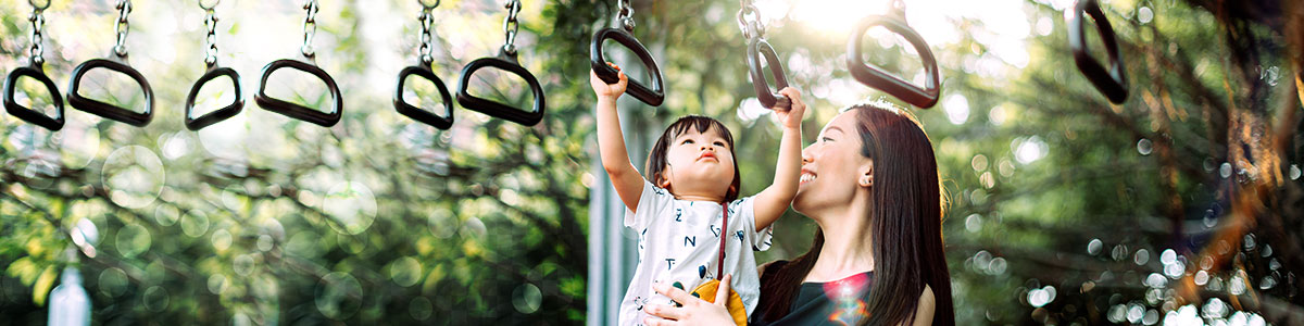 woman holding daughter up on playground