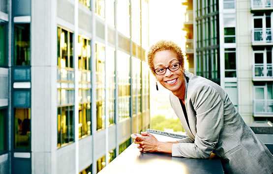 Smiling woman in a business suit leaning on a balcony