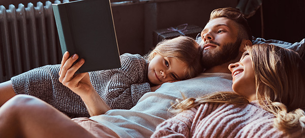 dad cuddling with two daughters reading a book