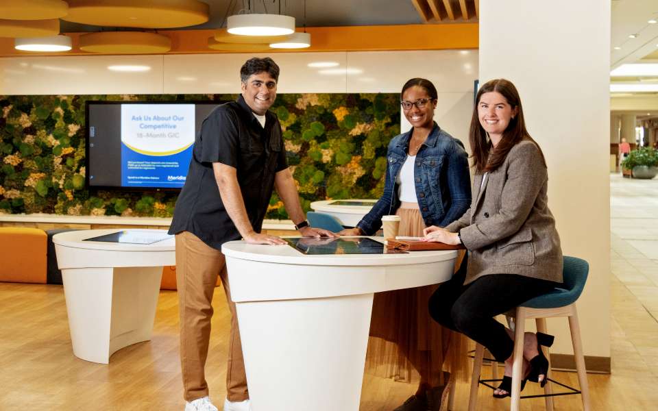 Three Meridian employees smiling together at a branch