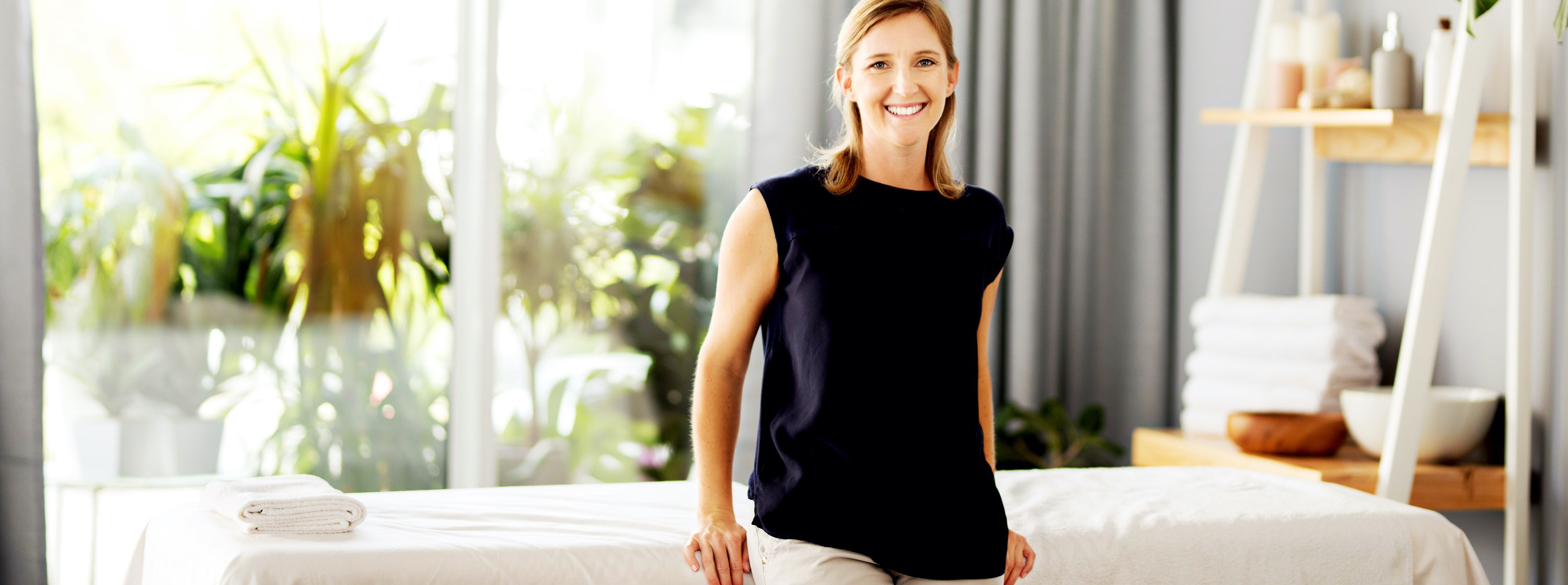 Woman stands in front of massage table in a spa.