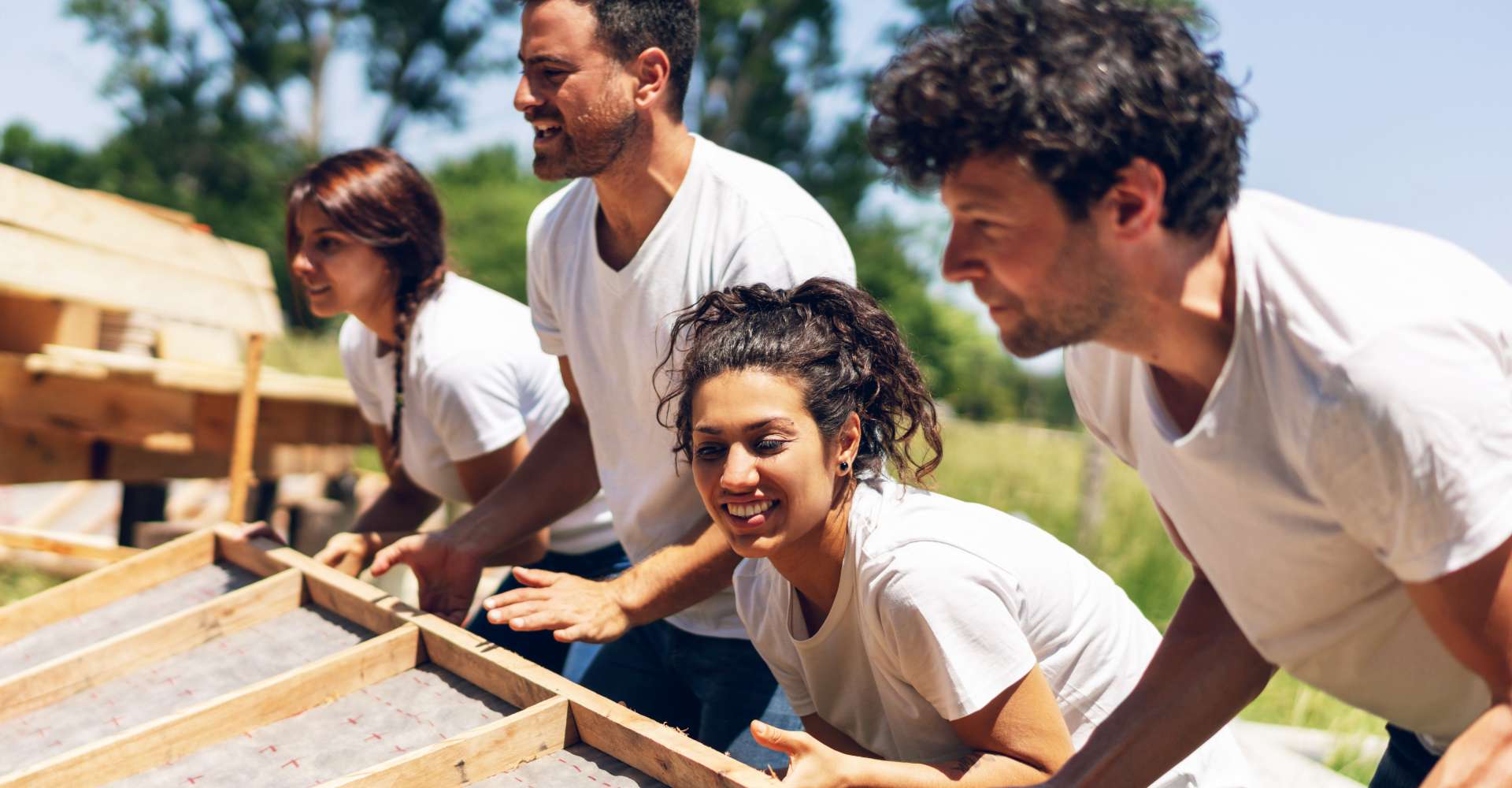 2 men and 2 women lifting a board