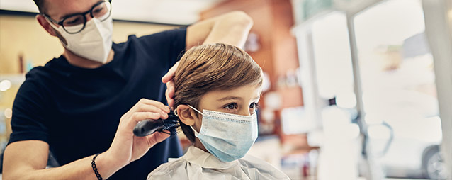 Boy in a mask getting a hair cut