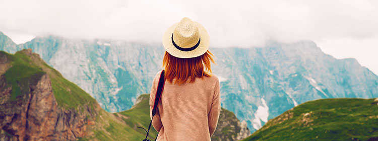 Women facing away from the camera staring out over mountains.