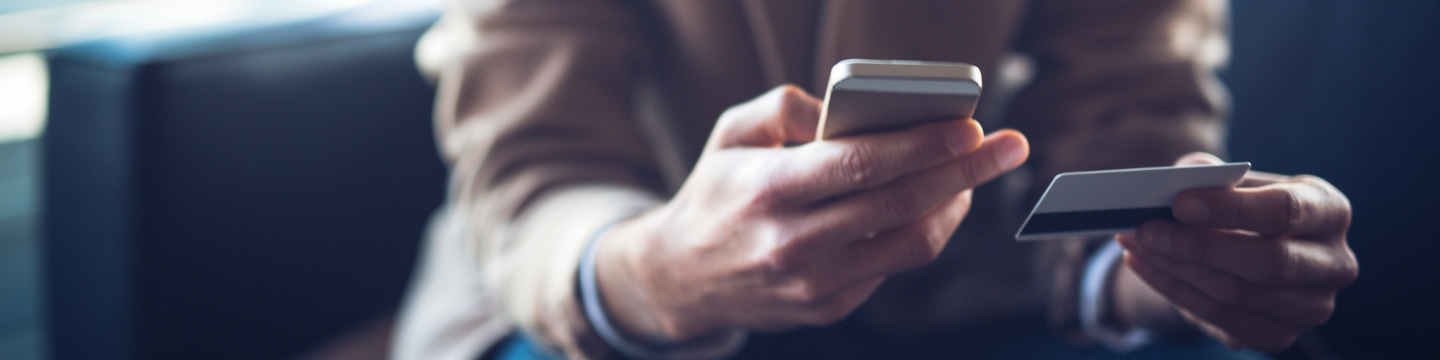 Close up of a hand holding a mobile phone while the other hand holds a credit card