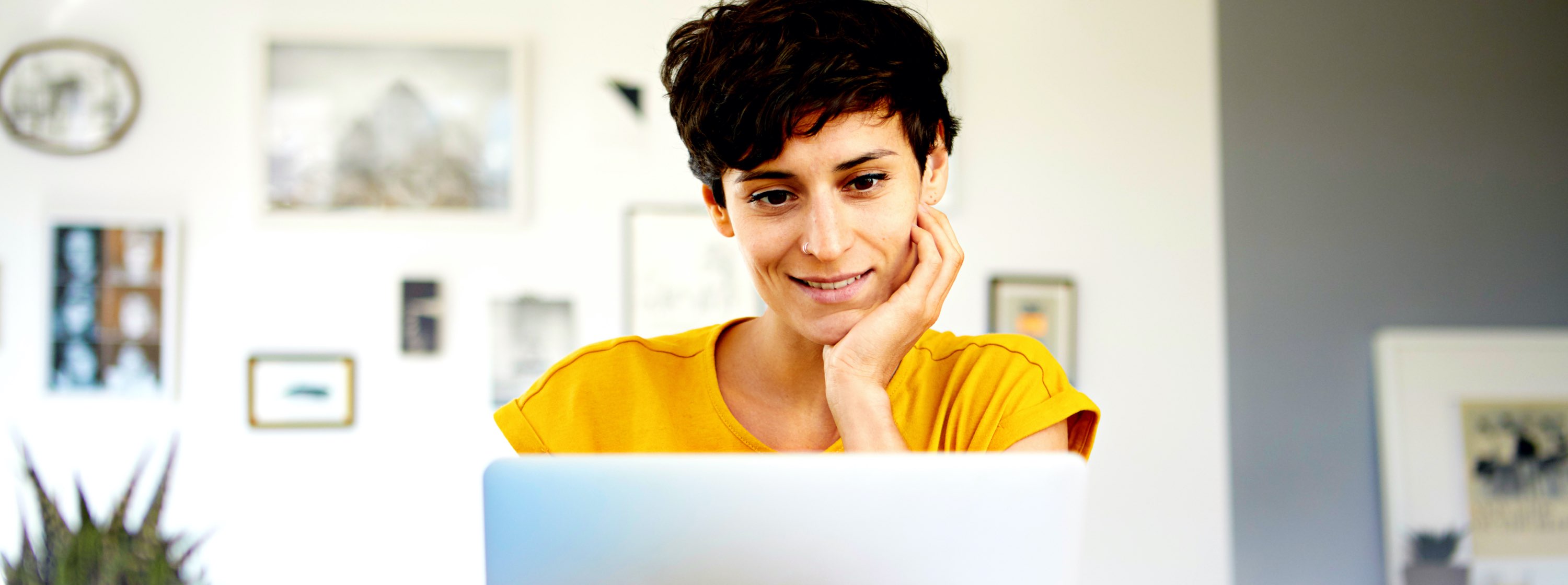 A woman sits in front of her computer, smiling.