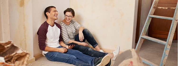 Couple laughing while taking a break from painting their home