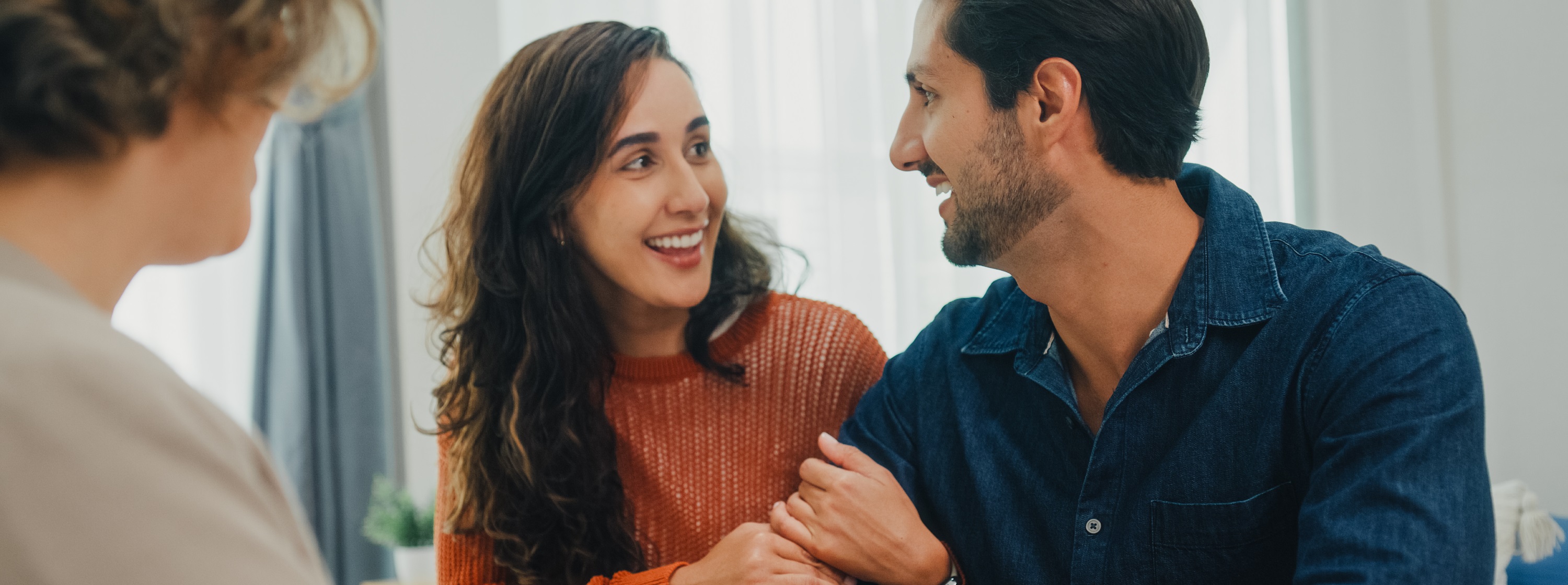 Smiling couple holding hands while speaking with an advisor