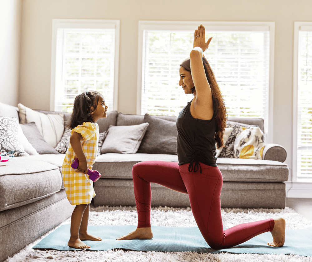 Mom and young daughter doing yoga in the living room