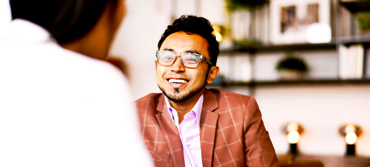 A man smiles as he shakes hands with his advisor