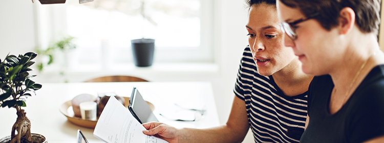 Two women reviewing documents, looking pensive.