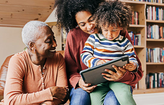 2 women and a kid looking at ipad