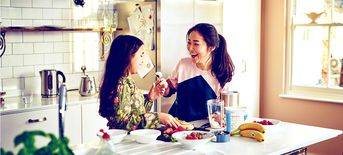mother and daughter taste testing in the kitchen