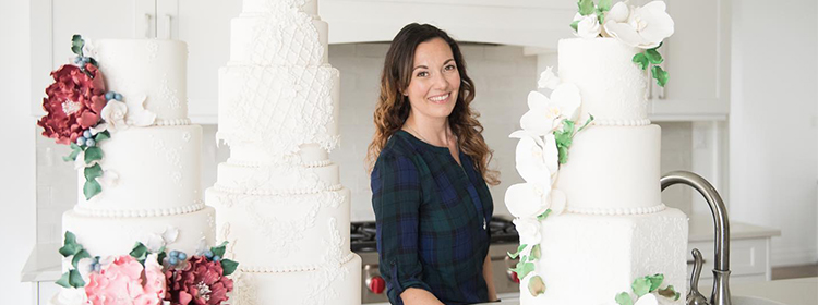  Martha Zacharias standing in her bakery in front of wedding cakes