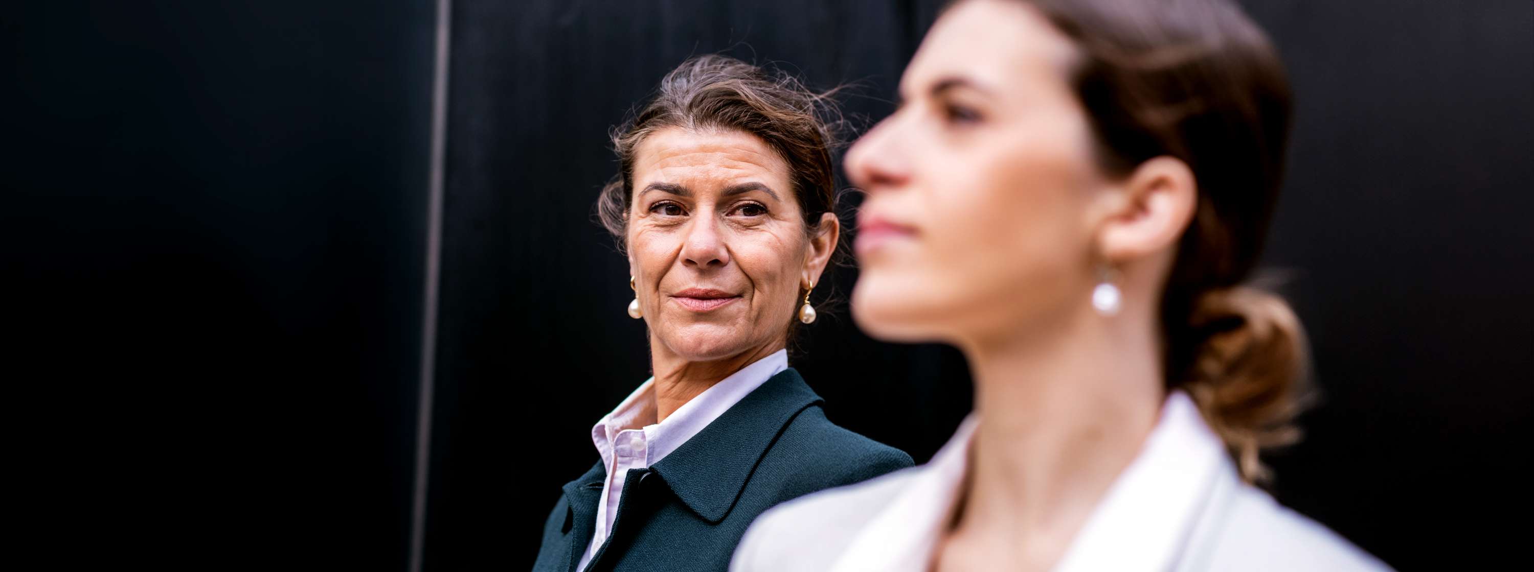 Two women, one mature and senior in age, the other middle-aged, engage in a calm conversation outdoors about the family business.