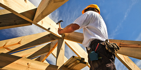 construction worker hammering wood to build a roof