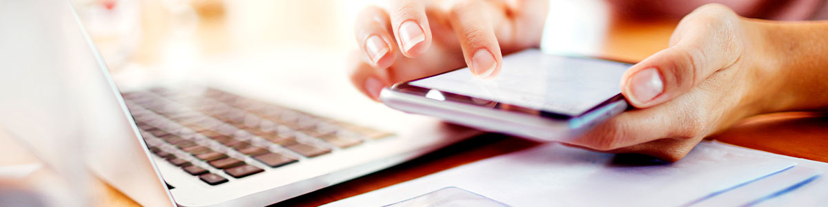 Person using a calculator next to a laptop