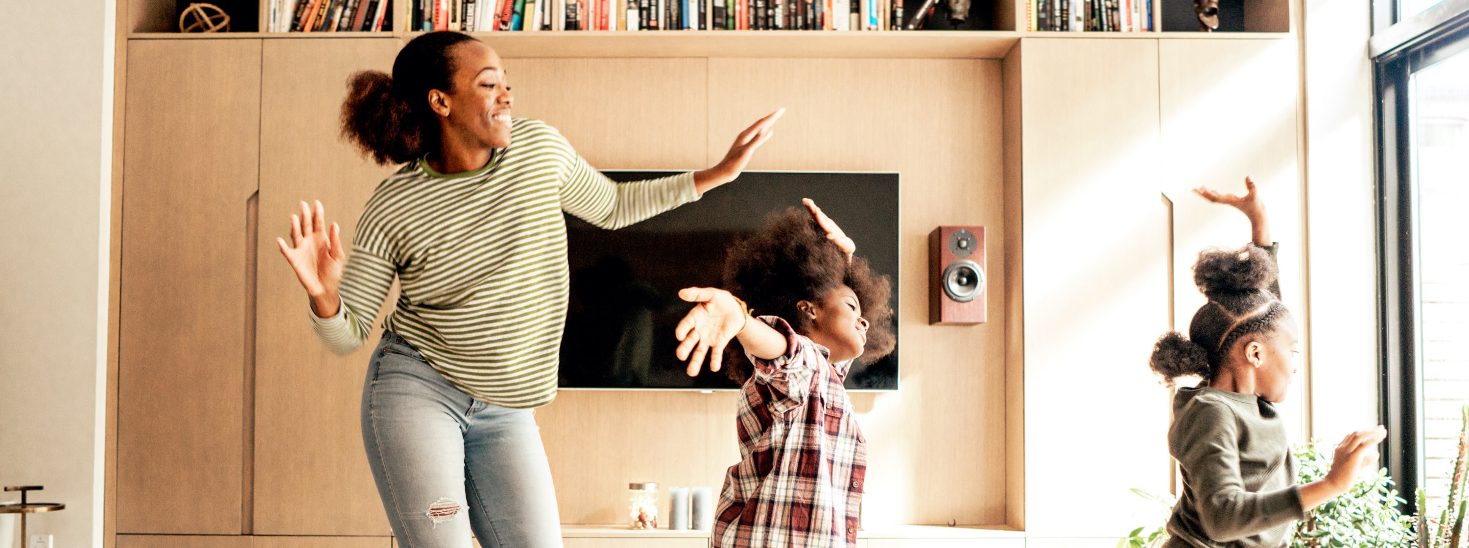 A mum and her kids dancing in the living room