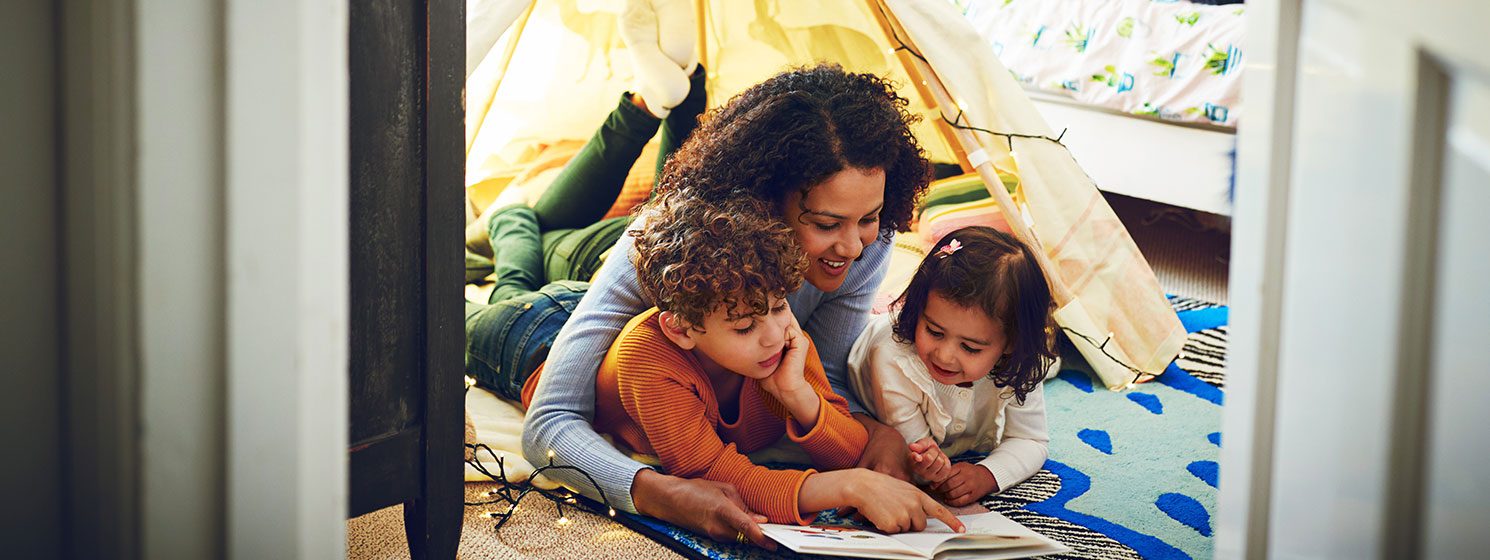 Smiling woman with son and daughter reading storybook.